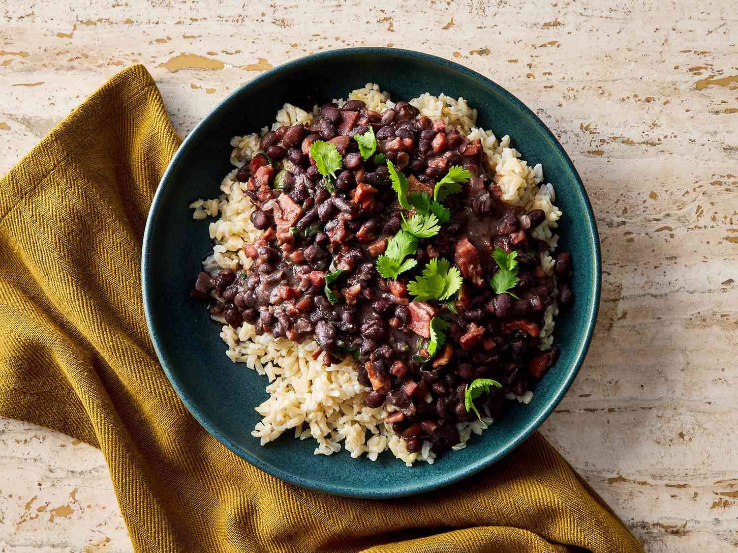Traditional Brazilian feijoada stew served in a clay pot with rice, collard greens, and orange slices